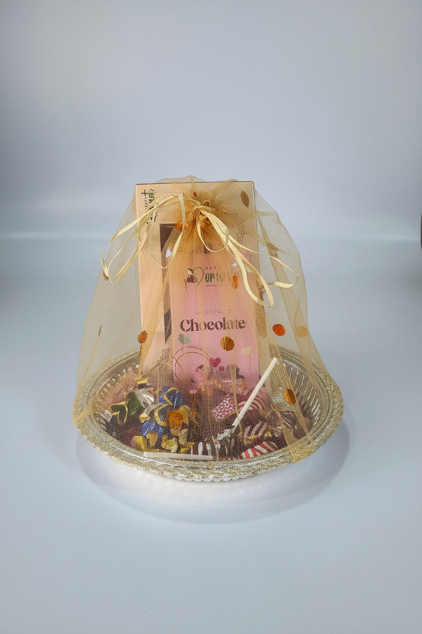 A chocolate hamper consisting of an assortment of chocolates packaged in a clear gift box with a golden ribbon and a pink label that reads 'Chocolate'.